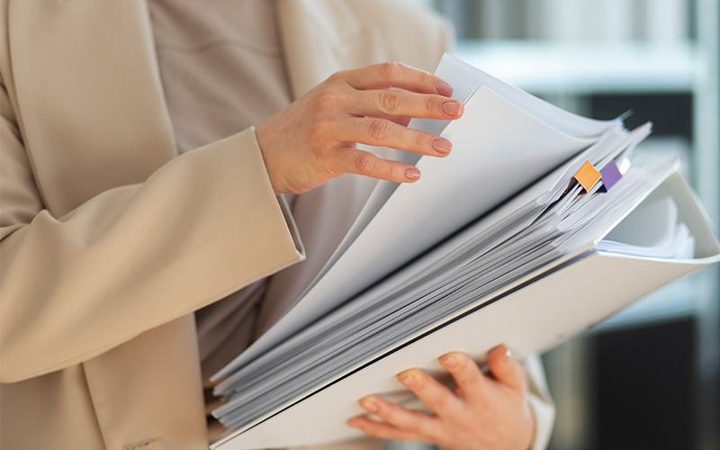 Credo professional reviewing thick binder of sustainability reports.
