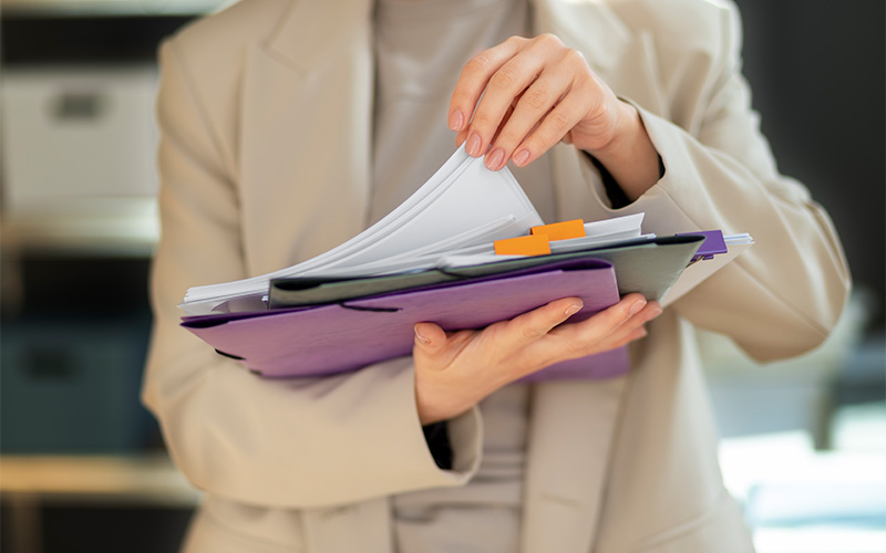 Person holding organized folders in office.