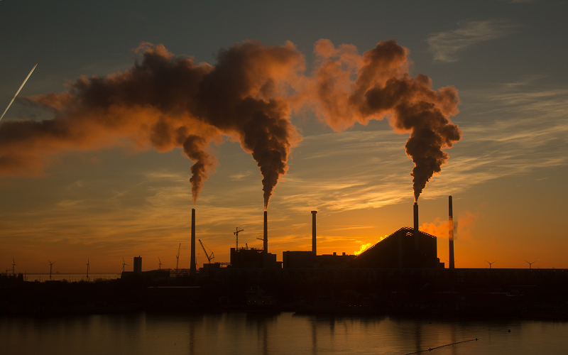 Industrial factory smokestacks releasing direct Scope 1 carbon emissions.