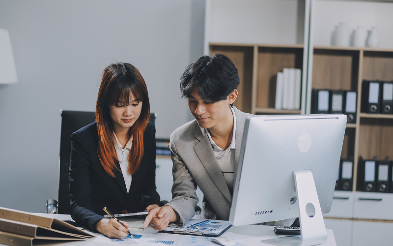 Executives reviewing ESG reporting compliance metrics together on computer.